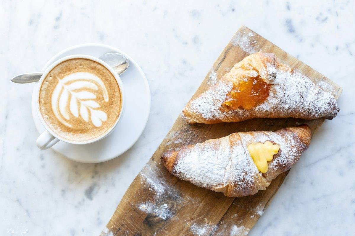 A cappuccino and two cornetti on a marble table