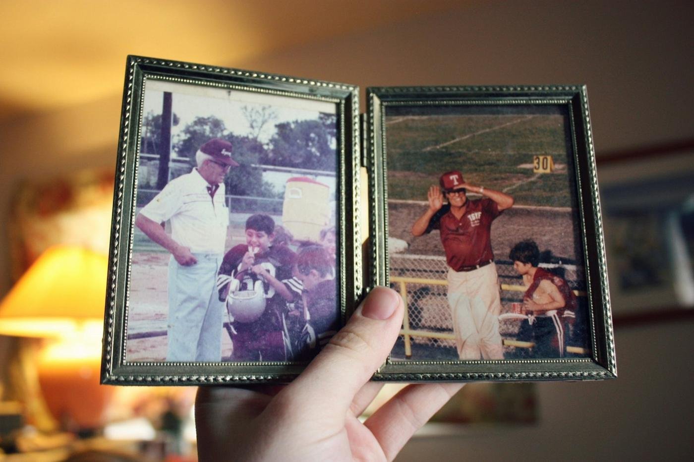 A hand holding old framed family photographs