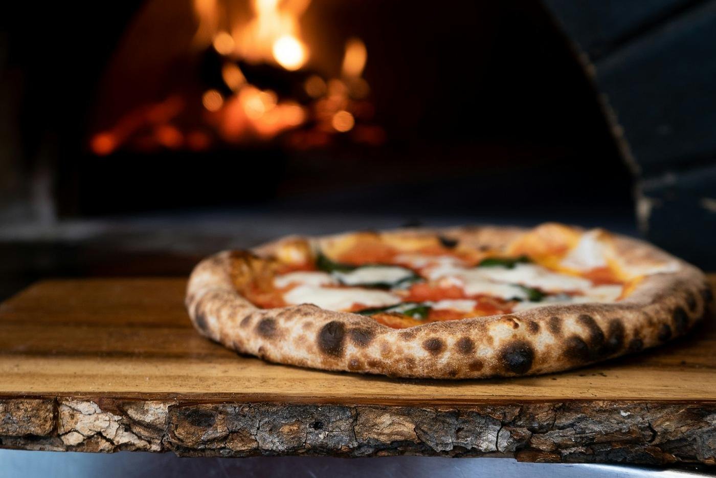 A pizza in front of a wood-fired oven