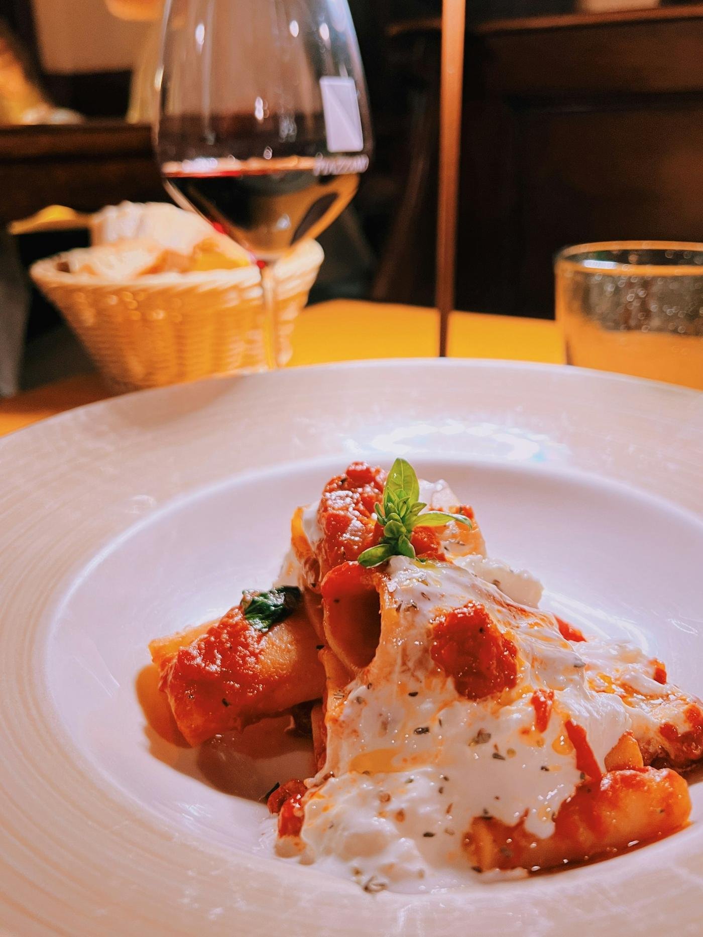 A plate of pasta and a glass of red wine at dinner