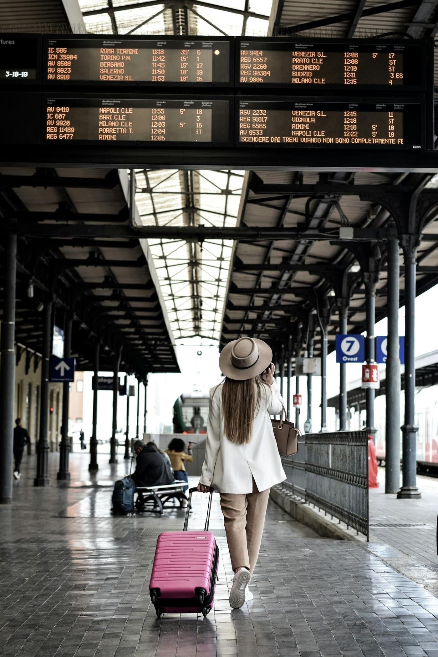 A traveler with her suitcase on a train platform in Italy
