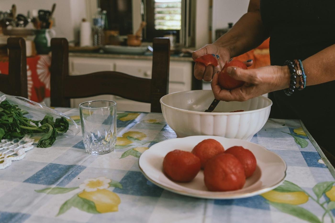 Fresh tomatoes being cut on a checkered tablecloth