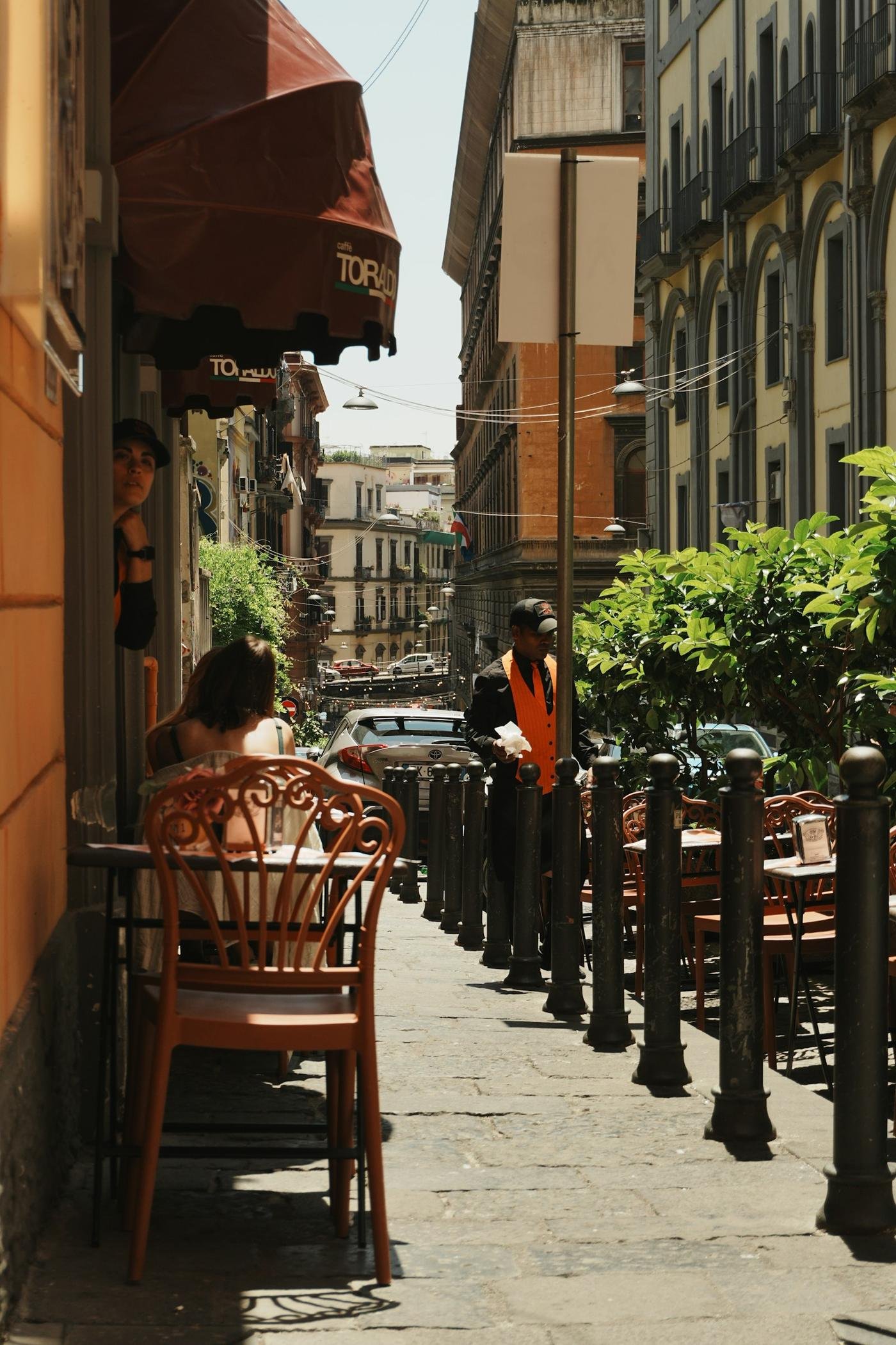 People chatting at an outdoor café in a narrow Italian street